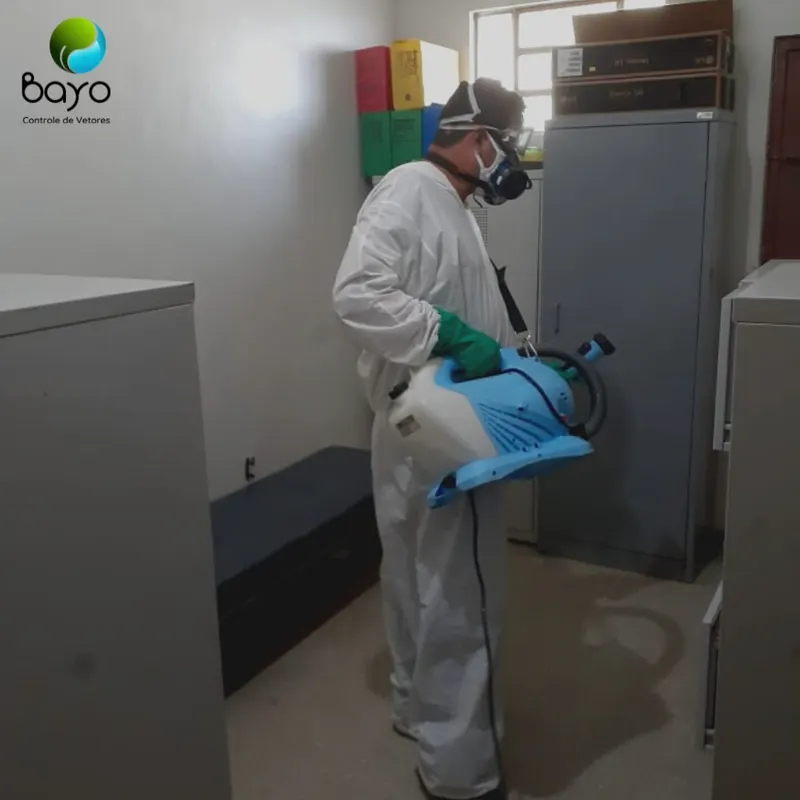 Técnico da Bayo de macacão e máscara fazendo aplicação em sala de arquivo
